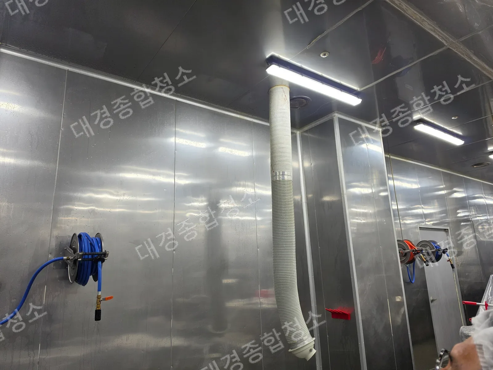 HACCP 위생 청소 작업 후 물기가 남은 식품공장 스테인리스 벽면과 호스릴