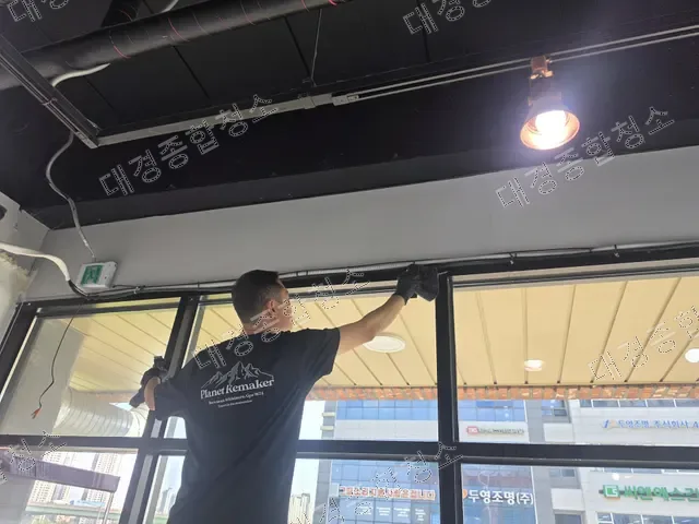 장대 밀대로 높은 천장 창틀을 청소하는 작업자