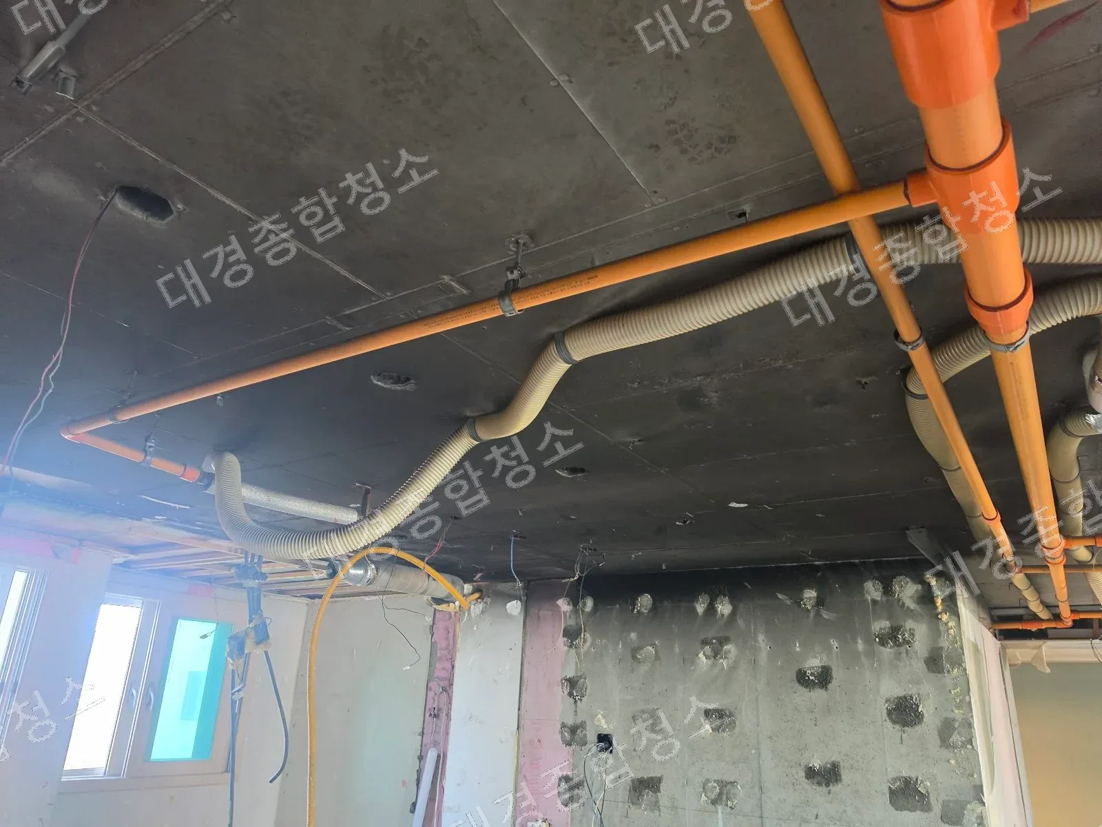 화재로 검게 그을린 천장과 오렌지색 배관, 그을음·검댕 제거 전 상태