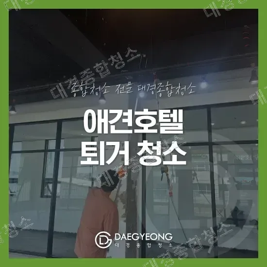 대형 유리창을 스퀴지로 닦는 청소 작업자